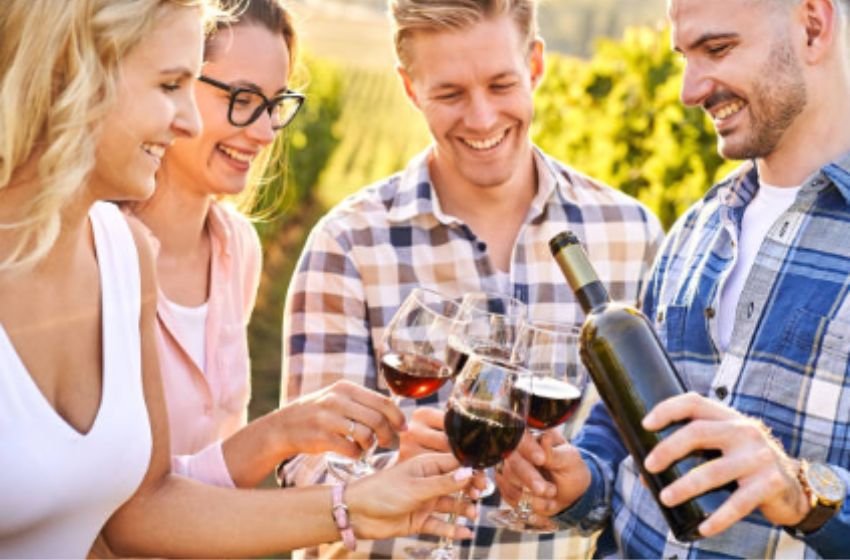 Pessoas degustando vinho e praticando enoturismo.